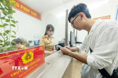 Cán bộ, chiến sỹ Công an phường Cửa Nam, thành phố Hà Nội tiếp nhận và hướng dẫn người dân đến làm thủ tục đăng ký xe môtô. (Ảnh: Phạm Kiên/TTXVN)