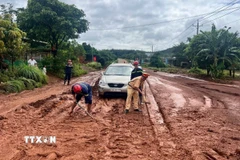 Lực lượng công an, dân quân địa phương khẩn trương dọn dẹp, khắc phục tình trạng sạt lở tràn ra Quốc lộ 14C gây ách tắc và nguy hiểm cho người tham gia giao thông. (Ảnh: TTXVN phát)