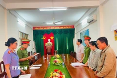 Cơ quan cảnh sát điều tra tống đạt các quyết định tố tụng đối với Trần Mỹ Tiên (áo carô). (Ảnh: TTXVN phát)