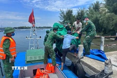Cán bộ chiến sỹ Đồn biên phòng Tam Thanh chuyển thi thể nạn nhân vào đất liền. (Ảnh: TTXVN phát)