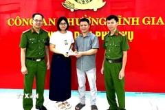 Công an phường Tĩnh Gia và chị Lê Thị Huyền trao trả lại tài sản cho người bỏ quên. (Ảnh: TTXVN phát)
