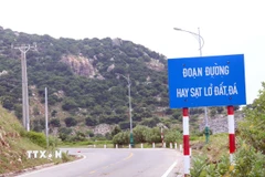 Lực lượng chức năng gắn biển cảnh báo tuyến đường hay xảy ra sạt lở để người và phương tiện thận trọng khi qua tuyến đường ven biển. (Ảnh: Công Thử/TTXVN)