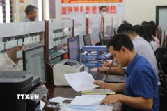 Chuyên viên lĩnh vực xây dựng, giao thông, công thương phường Thiên Hương kiểm tra thông tin hồ sơ công dân nộp. (Ảnh: Minh Thu/TTXVN)