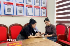Lãnh đạo Trung tâm phục vụ hành chính công xã Kỳ Thượng (tỉnh Hà Tĩnh) trực tiếp hướng dẫn người dân đăng ký hồ sơ trực tuyến. (Ảnh: Hữu Quyết/TTXVN)