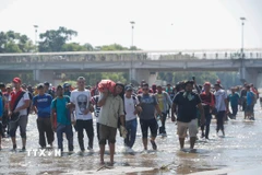 Người di cư Trung Mỹ vượt sông Suchiate từ Guatemala để tới Mexico, trong hành trình đến Mỹ. (Ảnh: THX/TTXVN)