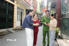 Tổ công nghệ số cộng đồng cùng cán bộ công an phường Phủ Lý, tỉnh Ninh Bình đến từng khu dân cư hướng dẫn người dân tham gia góp ý dự thảo các văn kiện Đại hội XIV của Đảng thông qua ứng dụng VNeID. (Ảnh: Nguyễn Chinh/TTXVN)
