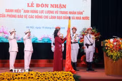 Phó Chủ tịch nước Võ Thị Ánh Xuân gắn huy hiệu “Anh hùng Lực lượng Vũ trang Nhân dân” lên lá cờ truyền thống Phòng Bảo vệ các đồng chí Lãnh đạo Đảng và Nhà nước thuộc Bộ Tư lệnh Cảnh vệ, Bộ Công an. (Ảnh: Phạm Kiên/TTXVN)