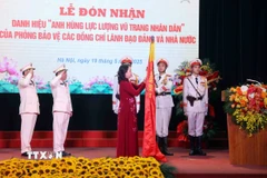 Phó Chủ tịch nước Võ Thị Ánh Xuân gắn huy hiệu “Anh hùng Lực lượng Vũ trang Nhân dân” lên lá cờ truyền thống Phòng Bảo vệ các đồng chí Lãnh đạo Đảng và Nhà nước thuộc Bộ Tư lệnh Cảnh vệ, Bộ Công an. (Ảnh: Phạm Kiên/TTXVN)