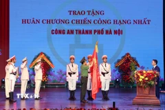 Đại tướng Lương Tam Quang, Bộ trưởng Bộ Công an gắn Huân chương Chiến công hạng Nhất lên lá cờ truyền thống của Công an thành phố Hà Nội. (Ảnh: Phạm Kiên/TTXVN)
