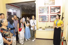 Thuyết minh viên hướng dẫn du khách tham quan tại Nhà trưng bày Bảo tàng Chiến thắng Điện Biên Phủ. (Ảnh: Xuân Tư/TTXVN)