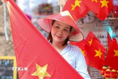 Người dân lưu lại khoảnh khắc với hình ảnh cờ Tổ quốc. (Ảnh: Khánh Hòa/TTXVN)