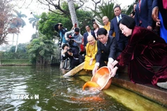 Chủ tịch nước Lương Cường và Phu nhân cùng kiều bào thả cá chép tiễn ông Công, ông Táo tại Ao cá Bác Hồ trong Khu Di tích Phủ Chủ tịch (Hà Nội). (Ảnh: Lâm Khánh/TTXVN)