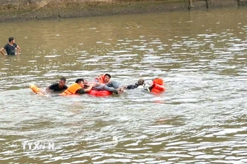 Lực lượng chức năng đưa thi thể nạn nhân đuối nước vào bờ. (Ảnh minh họa: TTXVN phát)