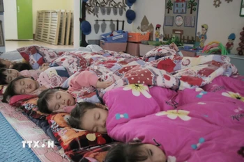 Đắp chăn cho trẻ em ngủ trưa tại lớp học.. (Ảnh: Đinh Thùy/TTXVN)