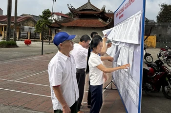 Người dân khu phố Phú Mẫn, thị trấn Chờ, huyện Yên Phong tìm hiểu các đề án sáp nhập. (Ảnh: Thái Hùng/TTXVN)