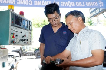 Ông Lê Tấn Thêm (ngoài cùng, bên phải) hướng dẫn thợ chế tạo những thiết bị công nghệ ứng dụng cho tàu cá. (Ảnh: Lê Phước Ngọc/TTXVN)