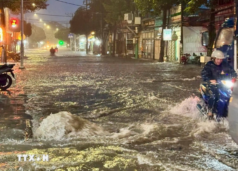 Nước ngập sâu, xoáy nước cuồn cuộn gây nguy hiểm cho người đi đường. (Ảnh: TTXVN phát)