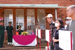 Lực lượng chức năng Việt Nam-Campuchia làm thủ tục bàn giao, tiếp nhận 15 công dân Việt Nam tại Cửa khẩu quốc tế Xa Mát, xã Tân Lập, tỉnh Tây Ninh. (Ảnh: Minh Phú/TTXVN) 