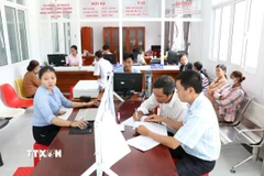 Người dân thực hiện thủ tục hành chính tại Trung tâm Phục vụ hành chính công xã Vinh Kim. (Ảnh: Thanh Hòa/TTXVN)
