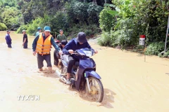 Hỗ trợ người dân ra khỏi vùng ngập lụt tại xã Mường Hung. (Ảnh: Quang Quyết/TTXVN)