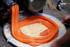 Xôi gấc làm bánh giầy được xay nhuyễn, có màu cam đỏ. (Ảnh: Thanh Hải/TTXVN)