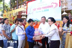 Phu nhân Tổng Bí thư, Chủ tịch nước Lào Naly Sisoulith trao phần quà yêu thương đầu tiên cho người khuyết tật. (Ảnh: Xuân Tú/TTXVN)