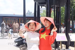 Người dân diện áo dài truyền thống, cờ đỏ sao vàng ghi lại những khoảnh khắc đẹp trong dịp lễ kỷ niệm. (Ảnh: Thu Hương/TTXVN)