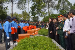Các đại biểu thực hiện nghi thức đưa hài cốt liệt sỹ đến nơi an nghỉ. (Ảnh: Nhựt An/TTXVN) 