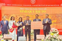 Lãnh đạo thành phố Hà Nội trao chứng nhận tặng tác phẩm tranh gỗ "Vinh Quy Bái Tổ" cho Trung tâm Hoạt động Văn hóa Khoa học Văn Miếu - Quốc Tử Giám. (Ảnh: Tuyết Mai/TTXVN)