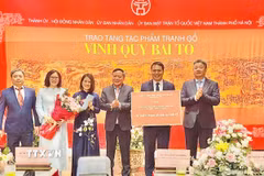 Lãnh đạo thành phố Hà Nội trao chứng nhận tặng tác phẩm tranh gỗ "Vinh Quy Bái Tổ" cho Trung tâm Hoạt động Văn hóa Khoa học Văn Miếu - Quốc Tử Giám. (Ảnh: Tuyết Mai/TTXVN)