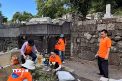 Các tình nguyện viên trồng hoa và dọn dẹp khu vực mộ phần Công nữ Ngọc Hoa tại Nagasaki. (Ảnh: Xuân Giao/TTXVN)