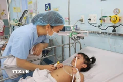 Nhân viên y tế Bệnh viện Nhi đồng 1 Thành phố Hồ Chí Minh chăm sóc bệnh nhi mắc tay chân miệng. (Ảnh: Đinh Hằng/TTXVN)