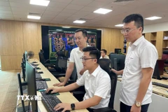 Kỹ sư Phạm Quang Tiến (ngồi giữa) cùng các đồng nghiệp đã đưa ra nhiều sáng kiến, giải pháp áp dụng tự động hóa quy trình làm việc. (Ảnh: Hoàng Hải/TTXVN)