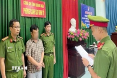 Lực lượng chức năng đọc quyết định khởi tố bị can đối với ông H.V.P. (Ảnh: TTXVN phát) 