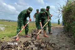Cán bộ, chiến sỹ Đồn Biên Phòng Tuy Hòa dọn bùn đất tại phường Phú Yên để người dân đi lại thuận tiện. (Ảnh: Tường Quân/TTXVN)