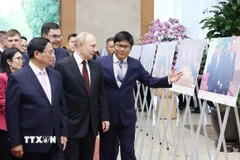 Thủ tướng Phạm Minh Chính và Tổng thống Liên bang Nga Vladimir Putin xem trưng bày ảnh về quan hệ hợp tác giữa hai nước do Thông tấn xã Việt Nam thực hiện. (Ảnh: Dương Giang/TTXVN)