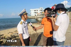 Các phóng viên Thắng Trung (cầm mic) và Sỹ Tuyên (TTXVN) quay phỏng vấn cán bộ hải quân trực tiếp làm nhiệm vụ canh gác bảo vệ trên đảo Đá Thị, Trường Sa hồi tháng 4/2021. (Ảnh: Phan Sáu/TTXVN)