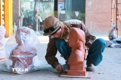 Người thợ căn chỉnh lại bức tượng truyền thần trước khi chuyển sang công đoạn đúc sản phẩm. (Ảnh: Công Luật/TTXVN)