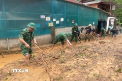 Cán bộ, chiến sỹ Đồn biên phòng Mường Ải (Nghệ An) giúp người dân địa phương dọn dẹp bùn đất, khắc phục hậu quả mưa lũ. (Ảnh: TTXVN phát) 