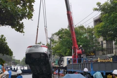 Lực lượng chức năng cẩu xe ô tô từ dưới hố lên. (Ảnh: Quốc Dũng/TTXVN)