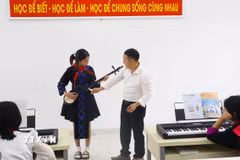 Giáo viên hướng dẫn học sinh sử dụng nhạc cụ dân tộc. (Ảnh: Phan Quân/TTXVN)