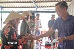 Phó Chủ tịch Uỷ ban Mặt trận Tổ quốc Việt Nam tỉnh Cà Mau Nguyễn Văn Khởi thăm hỏi, động viên và trao hỗ trợ cho 9 hộ dân bị thiệt hại trong vụ cháy. (Ảnh: TTXVN phát)