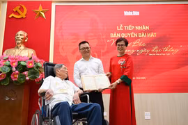 Tổng Biên tập Lê Quốc Minh nhận bản thảo bài hát "Như có Bác trong ngày đại thắng" có chữ ký đề tặng của nhạc sỹ Phạm Tuyên. (Ảnh: CTV/Vietnam+) 