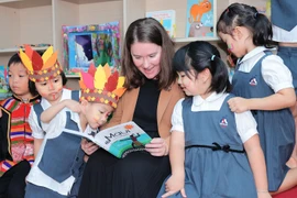 Phó Đại sứ New Zealand tại Việt Nam đọc sách cho các em thiếu nhi.(Ảnh: PV/Vietnam+)