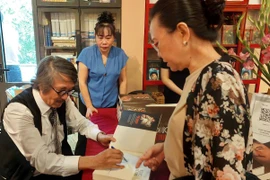 Tiến sỹ Nguyễn Thế Hùng ký tặng sách cho độc giả. (Ảnh: Minh Thu/Vietnam+)