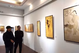 Khách tham quan chiêm ngưỡng một số tác phẩm (mô phỏng) của họa sỹ Trần Phúc Duyên tại Trường Đại học Mỹ thuật Việt Nam. (Ảnh: Minh Thu/Vietnam+)