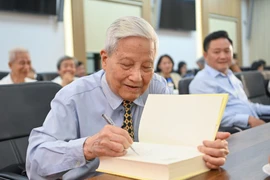 Nhà báo Hà Đăng ký tặng tại Lễ ra mắt sách. (Ảnh: PV/Vietnam+)