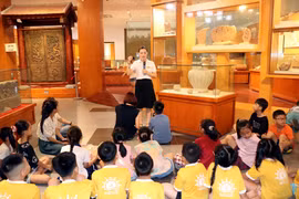 Cán bộ Bảo tàng tỉnh Ninh Bình giới thiệu những hiện vật được lưu giữ tại bảo tàng cho các em học sinh. (Ảnh: Nguyễn Lành/TTXVN)