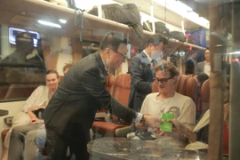 Ông Lê Quốc Minh, Ủy viên Trung ương Đảng, Tổng Biên tập Báo Nhân Dân, Phó Trưởng Ban Tuyên giáo và Dân vận Trung ương, Chủ tịch Hội Nhà báo Việt Nam lì xì cho hành khách trên Chuyến tàu Hạnh phúc. (Ảnh: PV/Vietnam+)