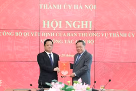 Phó Bí thư Thường trực Thành ủy Hà Nội Nguyễn Văn Phong trao quyết định của Ban Thường vụ Thành ủy Hà Nội và tặng hoa chúc mừng ông Vũ Minh Tuấn. (Ảnh: Quang Thái)